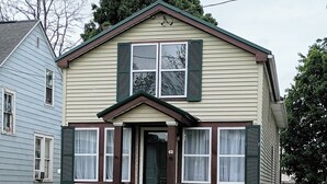 A two-story house with a front porch, a small garden, and a number '43' on the door.