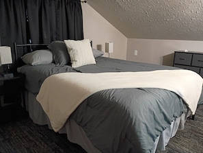 A hotel room with a bed, bedside tables, a lamp, and a nightstand.