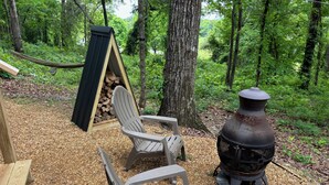 Une terrasse en bois avec des fauteuils Adirondack et une pile de bois.