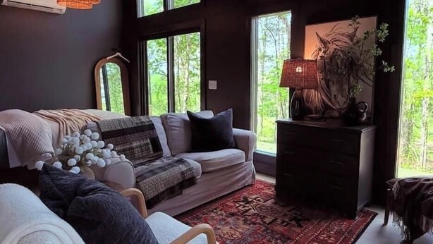 Un salon moderne comprenant un canapé, un fauteuil, un tapis, une lampe et une statue de cheval décorative.