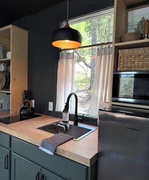 Eine moderne Küche mit integriertem Spülbecken, Wasserkocher, Mikrowelle und Kühlschrank.
