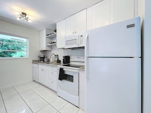A kitchen with white cabinets, a white refrigerator, a microwave, and a stove. - Chic Boho Paradise: Las Olas (Oakland Park)