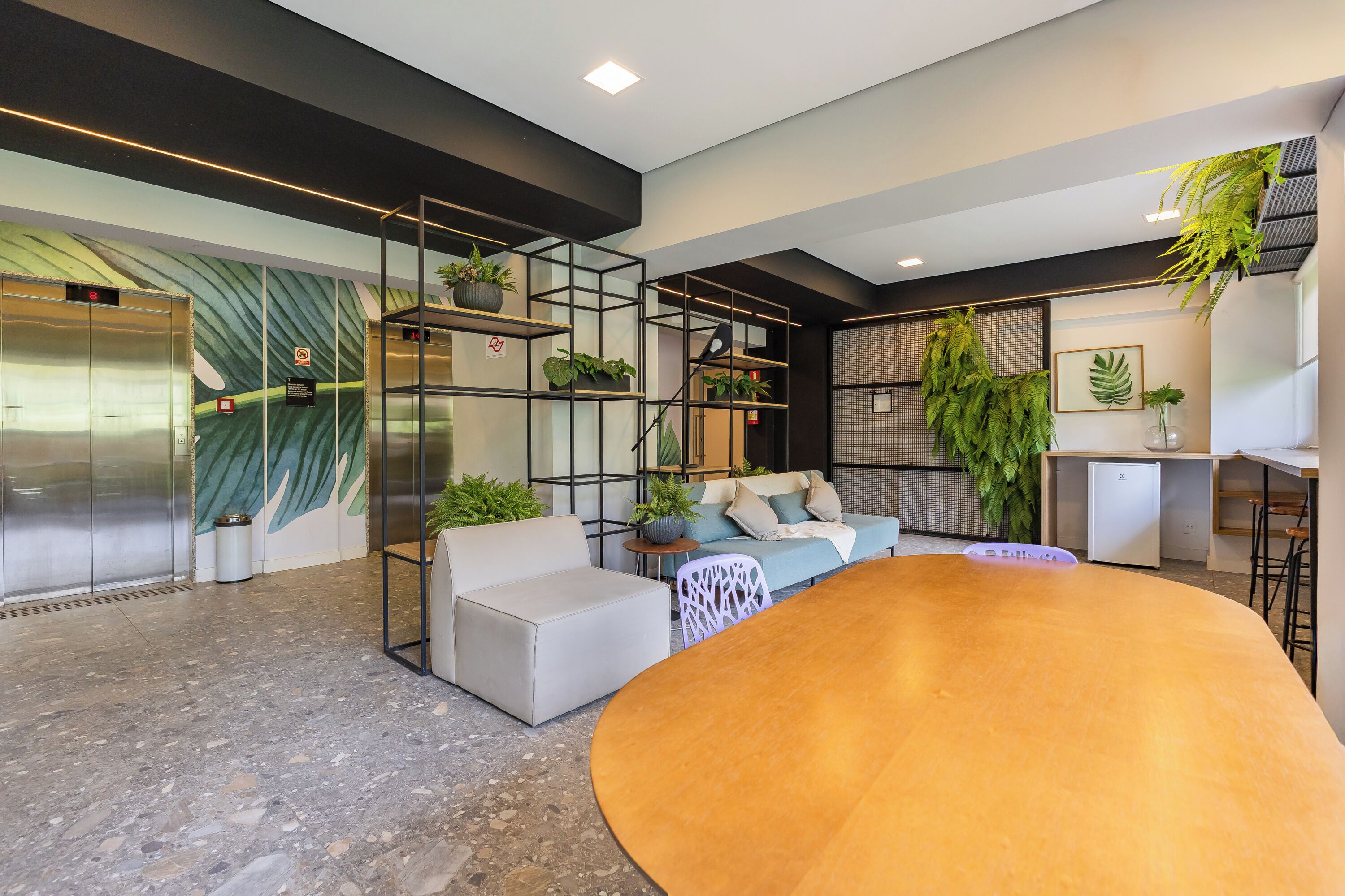 Um interior moderno com um sofá, uma mesa redonda e uma escada com guarda-corrimão de vidro.