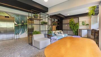 Um interior moderno com um sofá, uma mesa redonda e uma escada com guarda-corrimão de vidro.