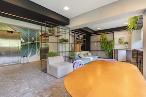 Um interior moderno com um sofá, uma mesa redonda e uma escada com guarda-corrimão de vidro.