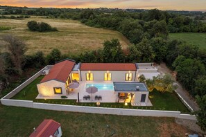 Ein modernes Haus mit Swimmingpool, umgeben von einem gepflegten Rasen und Bäumen.