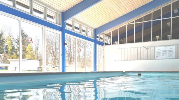 En inomhuspool med klart vatten, stora fönster och en färgskala i blått och vitt.