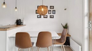 Ett modernt kök med en vit bänkskiva, två bruna stolar och en hängande lampa.