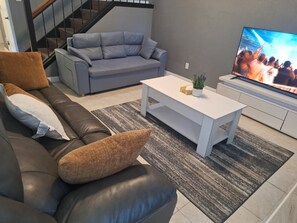 A living room with a sofa, a coffee table, and a TV. - 4BR/3BT Spacious Family Retreat,Quick Access to Downtown perfect for Group Stays (Dallas)