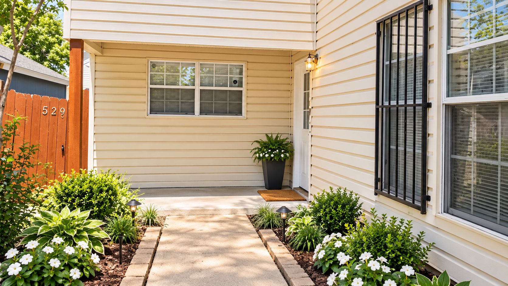 A house with a front porch, a wooden fence with the number 529, and a potted plant.