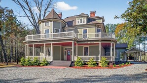 A two-story house with a wrap-around porch, a separate garage, and a small detached structure. - Two Dining Tables · Sleeps 14 · 7BR, 4 Baths (Fuquay-Varina)