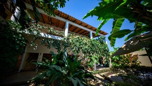 A building with a tiled roof, covered in greenery, and a staircase leading to an entrance. - Hidden Garden Oasis - Ground Floor + Pool (Lo de Marcos)