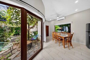 A dining area with a table and chairs, a ceiling fan, and a view of a garden through glass doors. - Hidden Garden Oasis - Ground Floor + Pool (Lo de Marcos)