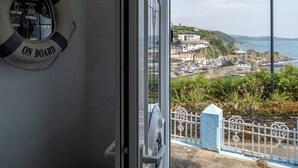 Vista desde el interior de un barco con un cartel que dice 'Welcome On Board', un pueblo costero con edificios y vista al mar.