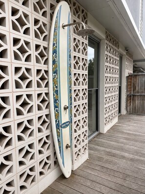 Un mur blanc orné d’un motif décoratif, avec une planche de surf appuyée contre.