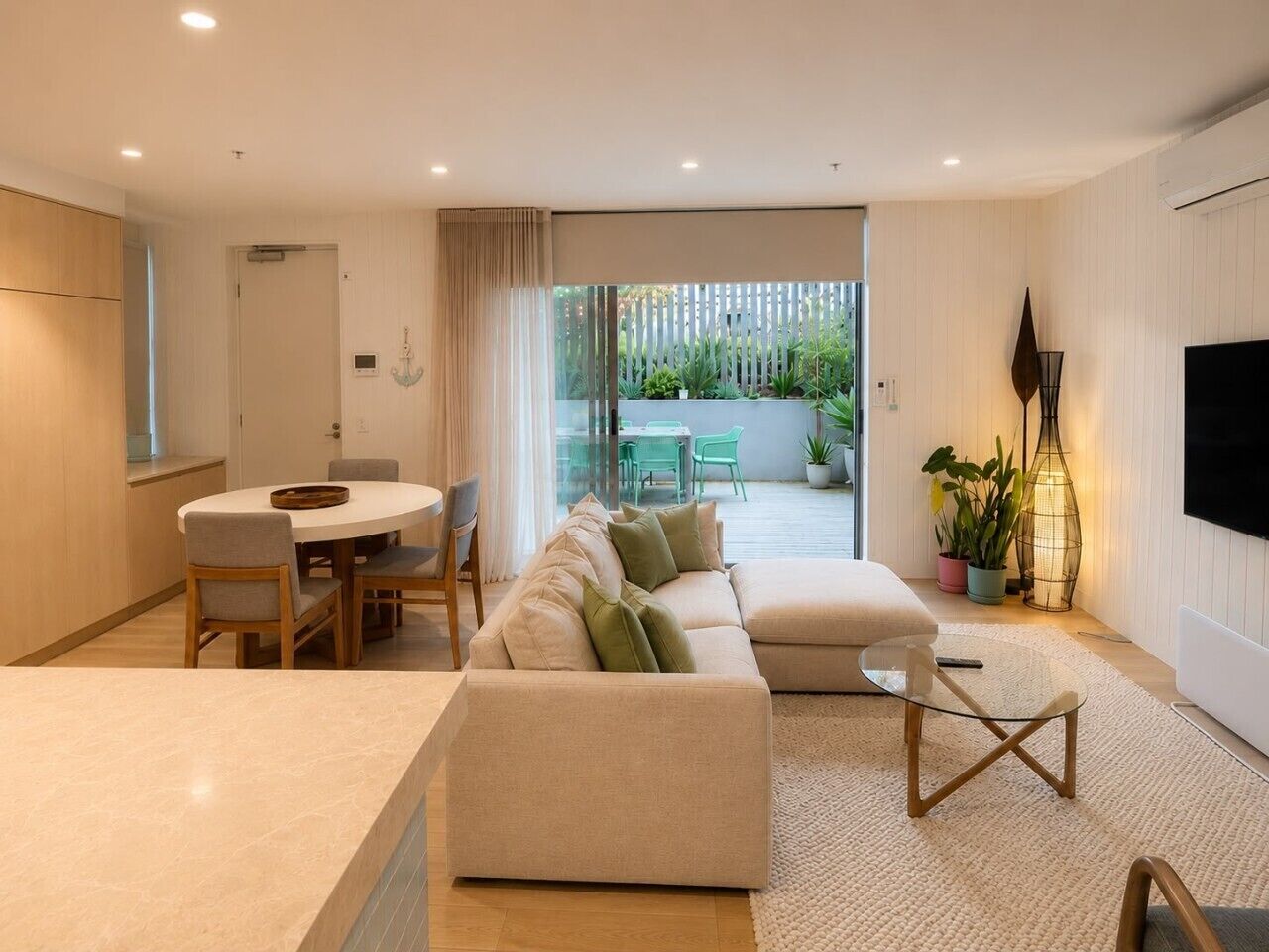 A modern living room with a sofa, a dining table, and chairs.