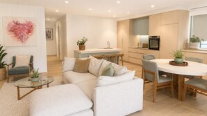 Ein modernes Wohnzimmer mit einer Couch, einem Glastisch und einem Essbereich mit rundem Tisch und Stühlen.