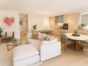 Un salon moderne avec un canapé, une table basse en verre et un coin repas comprenant une table ronde et des chaises.