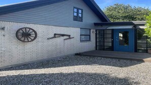 A building with a white exterior, a blue door, and a wheel mounted on the wall.