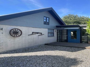 Ein Gebäude mit weißer Fassade, einer blauen Tür und einem an der Wand befestigten Rad.