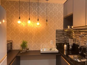 Eine moderne Küche mit Pendelleuchten, einer Spritzschutzwand und einer Arbeitsplatte mit einer Kaffeemaschine.