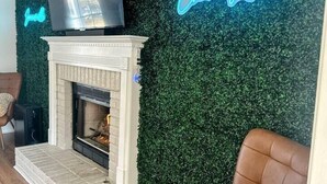A living room with a fireplace, a television, and a neon sign. - Summerville’s Charm House (Summerville)