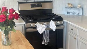 A kitchen with a stove, oven, microwave, and a wooden table with a vase of flowers. - Summerville’s Charm House (Summerville)