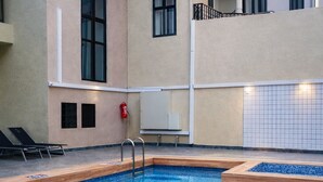 An indoor swimming pool with clear blue water, a ladder, and lounge chairs. - KIGALI GOLDEN VILLA RESORTS WITH POOL (Kigali)
