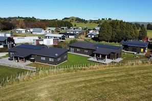 Een woonwijk met moderne huizen, voorzien van zonnepanelen, omgeven door groene velden en bomen.