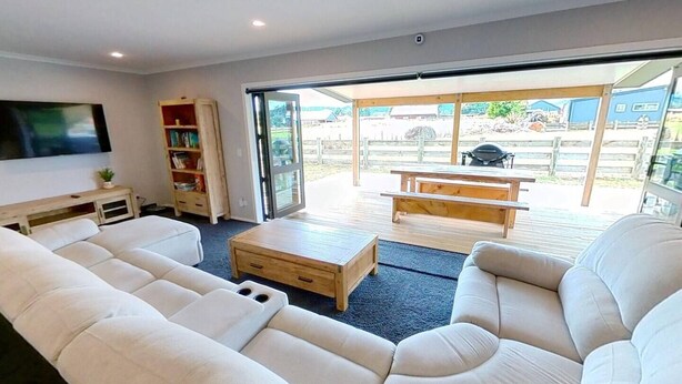 Una sala de estar con sofá, mesa de centro, estantería y televisor.