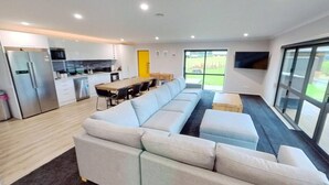 Una sala de estar moderna con un sofá, una mesa de comedor con sillas, una zona de cocina y un ventanal grande.