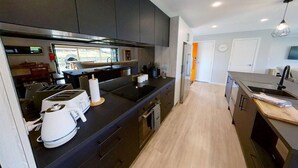 Una cocina moderna con armarios oscuros, una isla central y un comedor con vistas.