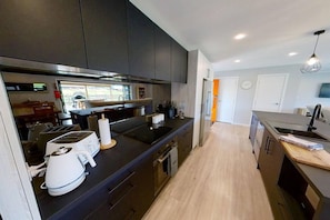 Una cocina moderna con armarios oscuros, una isla central y un comedor con vistas.