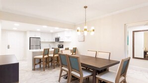 Eine moderne Küche mit weißen Schränken, Edelstahlgeräten und einem Essbereich mit Holztisch und Stühlen.