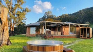 Ett modernt hus med en bubbelpool, en täckt uteplats och utsikt över den omgivande skogen.