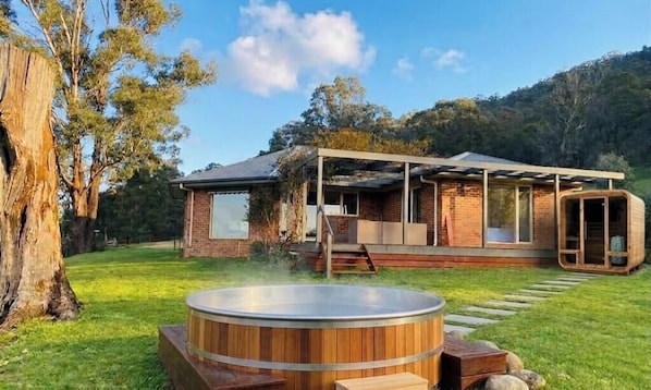 Ein modernes Haus mit Whirlpool, überdachter Terrasse und Blick auf den umliegenden Wald.