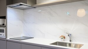 Una cocina moderna con salpicadero de mármol blanco, pileta de acero inoxidable y horno empotrado.
