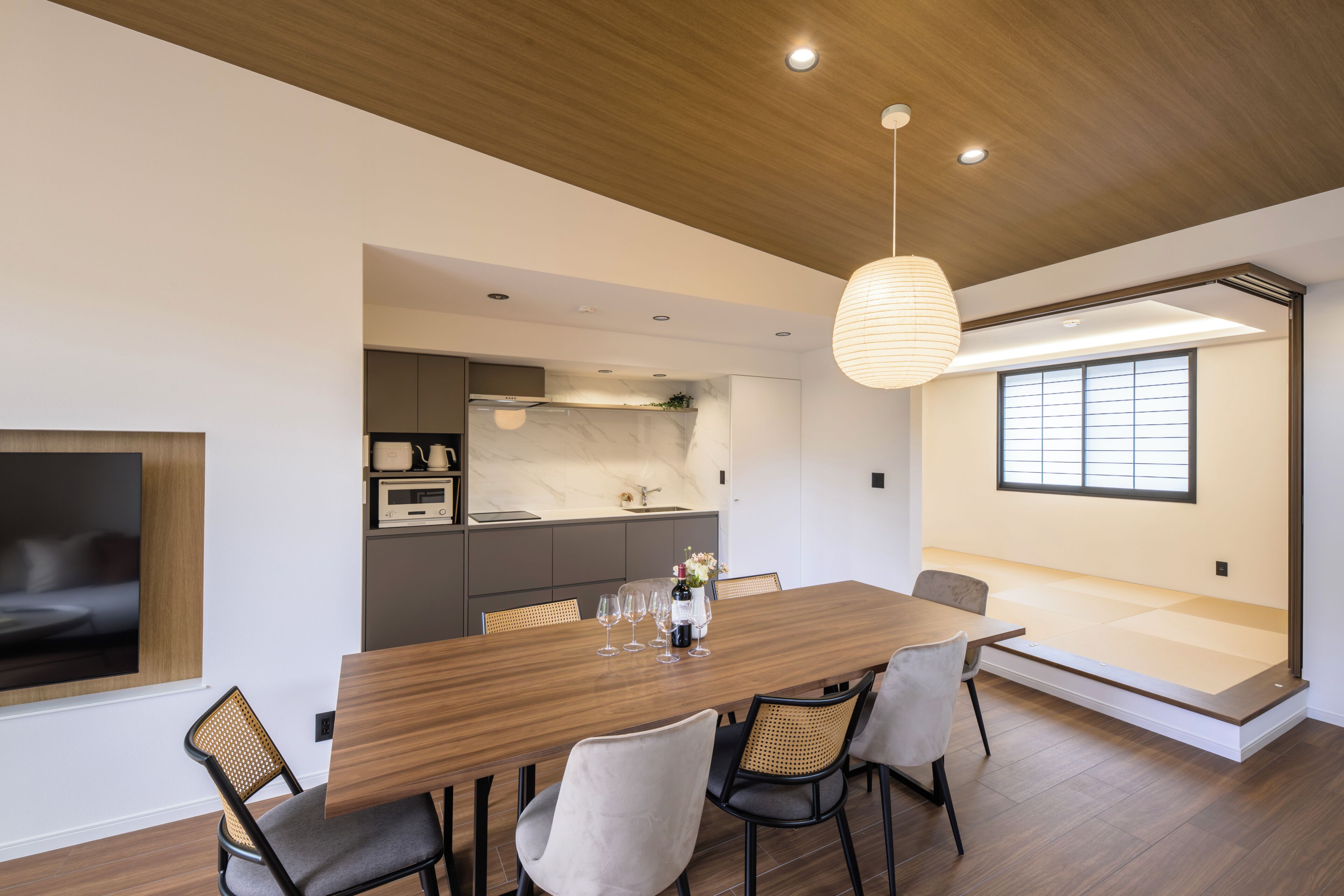 Un comedor moderno con una mesa de madera, sillas e iluminación colgante.