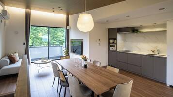 Una cocina moderna con encimera de mármol, un comedor con mesa y sillas de madera, y una sala de estar con sofá y televisor.