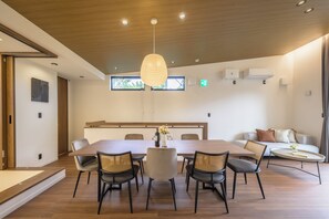 Un comedor moderno con una mesa de madera, sillas y una lámpara colgante.
