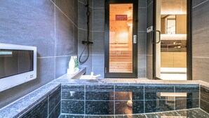 Un baño moderno con ducha, tocador con espejo y pantalla digital.
