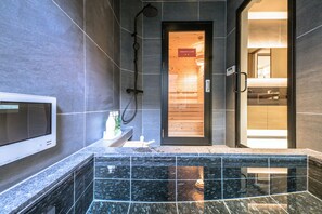 Un baño moderno con ducha, tocador con espejo y pantalla digital.