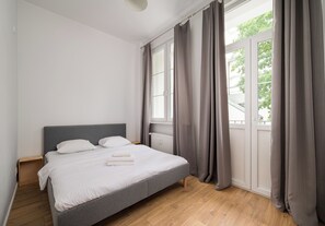 A bedroom with a bed, curtains, a window, and a radiator. - Miodowa Royal Old Town Apartment (Warszawa)