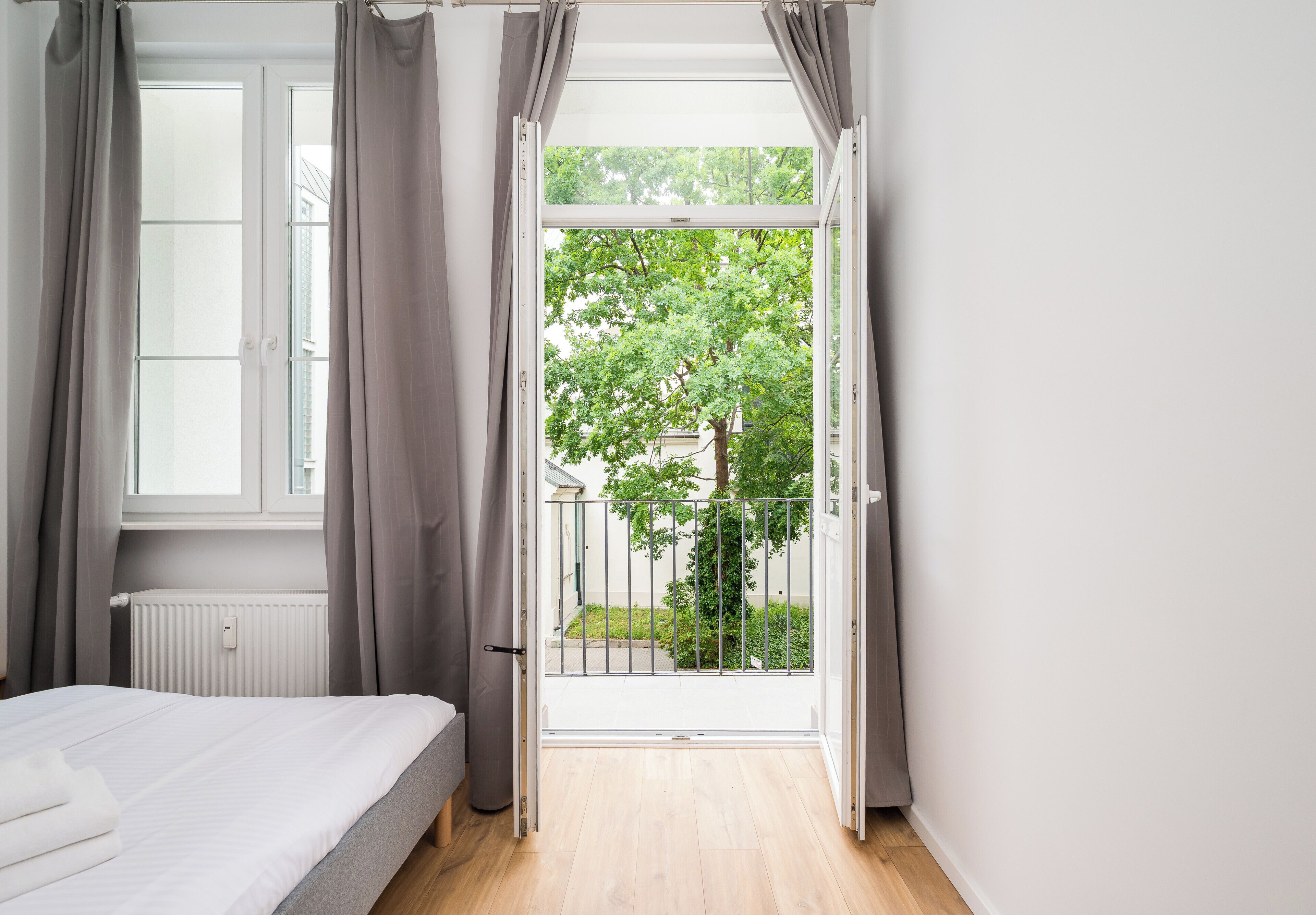 Un dormitorio con una cama, una ventana y vistas a un árbol y una valla.