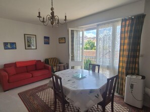 Ein Zimmer mit Esstisch, rotem Sofa und Heizkörper.