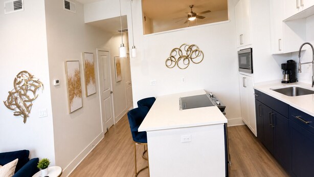 Una cocina moderna con una isla central, luces colgantes y un ventilador de techo.