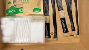 A wooden box containing eco-friendly floss picks, bamboo charcoal toothbrushes, and cotton swabs.