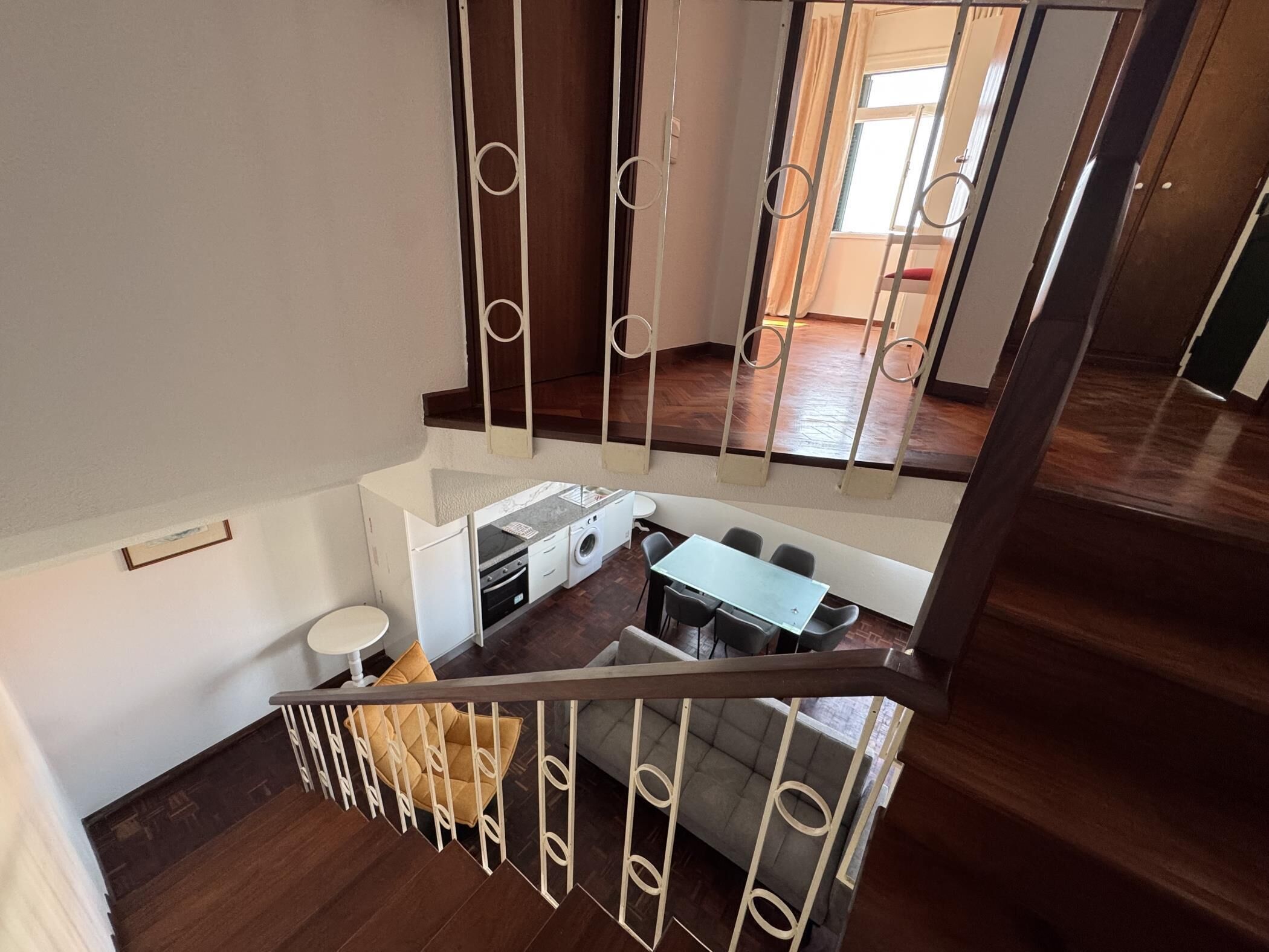 A multi-level interior with a kitchen area, a dining table, and a staircase.