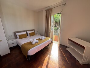 Ein Hotelzimmer mit Bett, Nachttisch, Schreibtisch, Stuhl und Blick ins Freie.