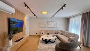 Een moderne woonkamer met een hoekbank, een flatscreen-tv, een salontafel en abstracte kunst aan de muur.